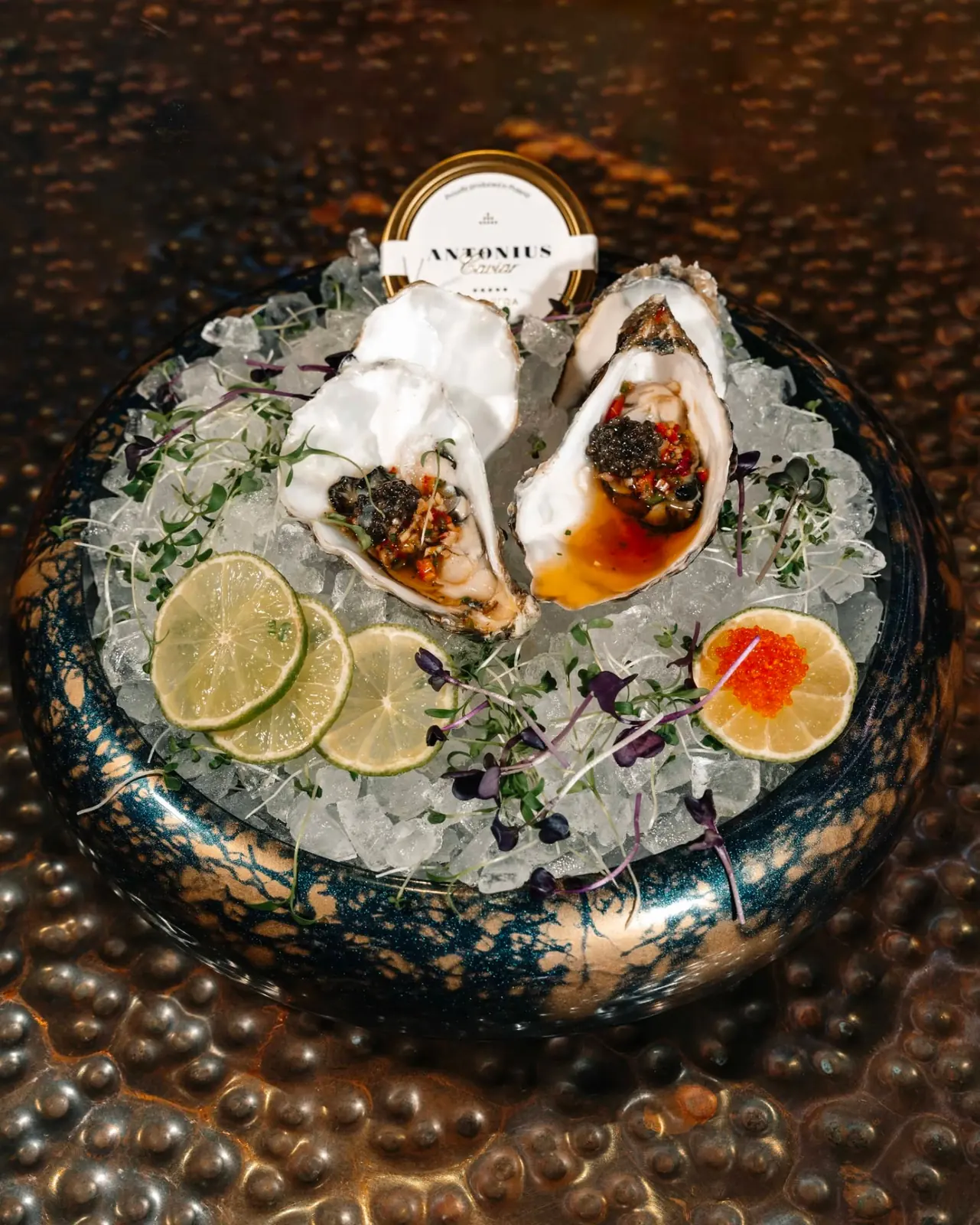 Oysters with caviar, ponzu and lime on crushed ice in a glazed bowl