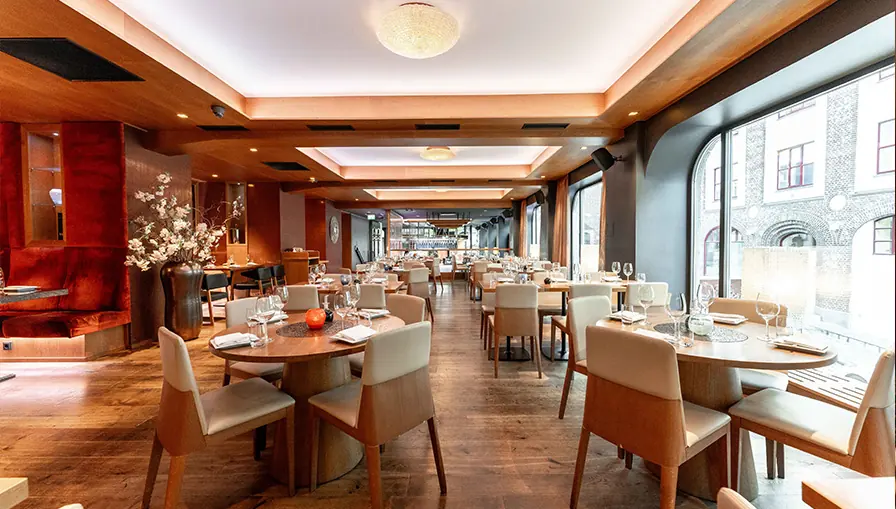 NAMA's dining room in Bergen with oak tables, arched windows and warm lighting