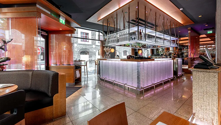 The illuminated bar counter at NAMA with bottles, glassware and lounge seating