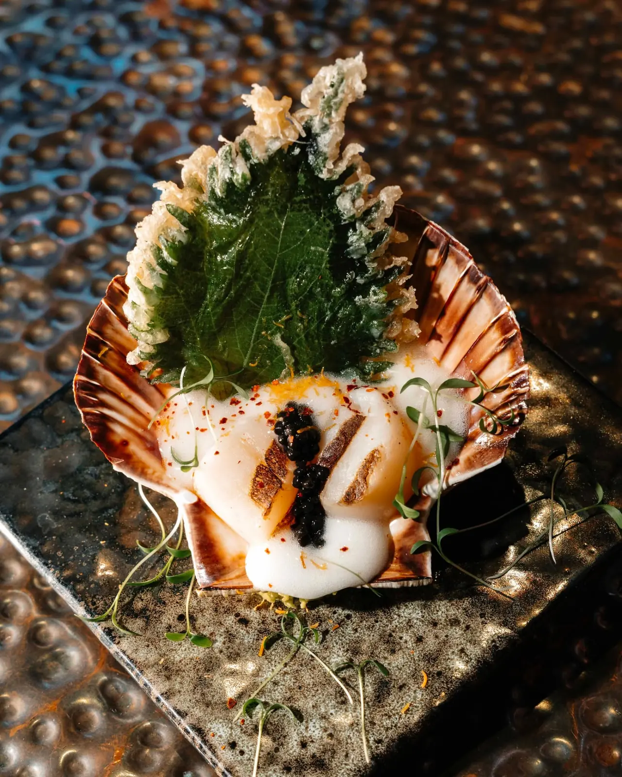 Norwegian scallop served in its shell with caviar, citrus foam and tempura shiso