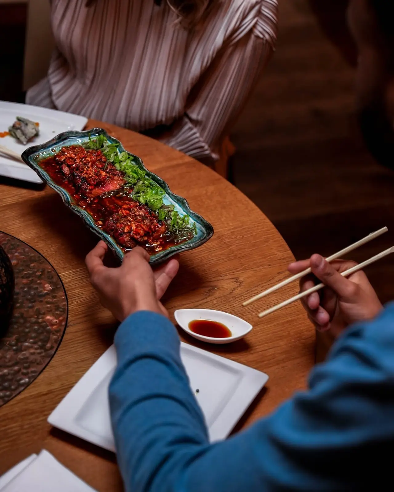 Grilled beef tataki with chilli relish and spring onion served on a turquoise ceramic plate