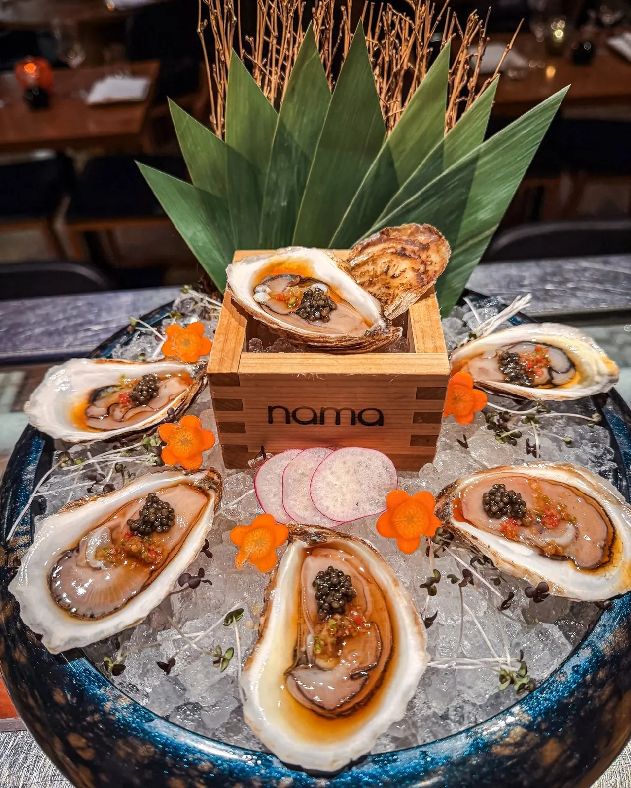 Oysters with caviar and ponzu on ice around a nama sake box