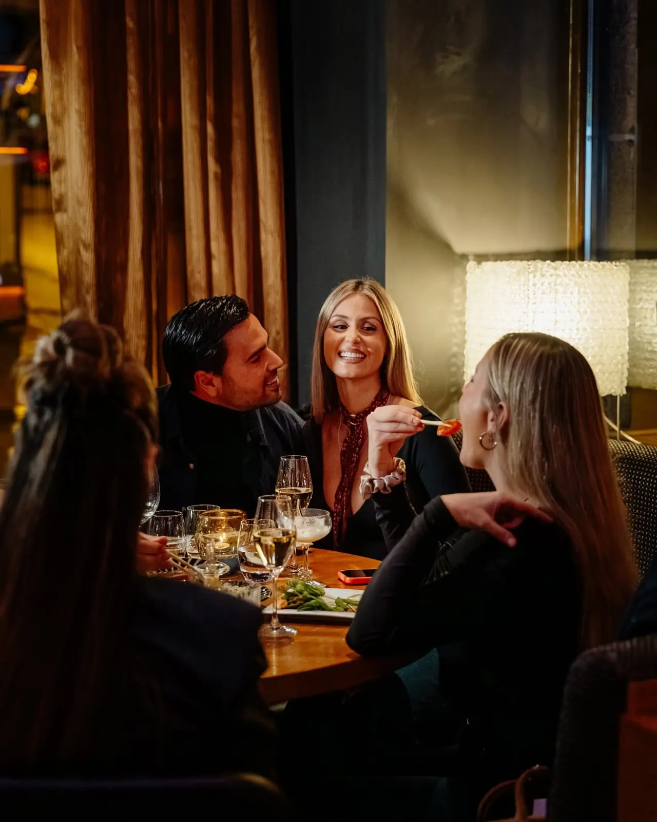 Guests laughing over sushi and champagne at a private table at NAMA